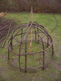 an outdoor sculpture made out of branches in the grass