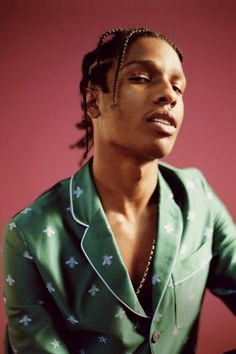 a woman with dreadlocks wearing a green shirt and beaded necklace looking off to the side