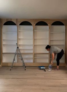 a woman is painting shelves in an empty room