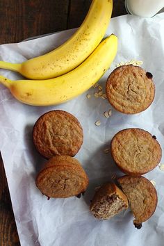 some muffins and bananas are sitting on a piece of paper next to a glass of milk