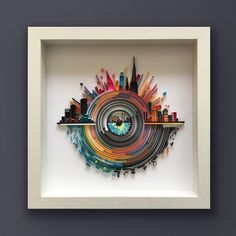 an art piece in a white frame with cityscape on the wall behind it