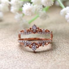 two wedding bands with diamonds on them sitting next to some white flowers and greenery