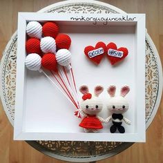 two stuffed animals in a white box with red and white balloons attached to them, on a wooden table