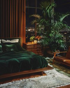 a bedroom with a bed, chair and plant in the corner by the window at night