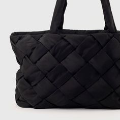 The Holiday Essential Tote by Urban Originals is a chic, sustainable bag with a woven front made from recycled nylon. This versatile tote features multiple compartments and practical pockets, making it perfect for everyday use or a weekend getaway. Effortlessly combining style and functionality, elevate your look with this eco-friendly essential. Versatile Intrecciato Travel Bag, Black Travel Bag With Intrecciato Weave, Black Intrecciato Travel Bag, Sustainable Bag, Holiday Essentials, Travel Wallets, Elevate Your Look, Weekend Getaway, Weekend Getaways