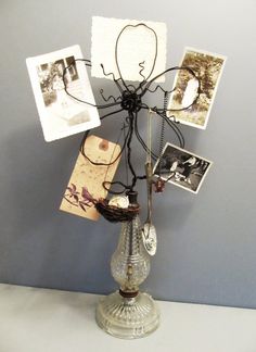 a glass vase with pictures on it and some wire attached to the top, sitting against a blue wall