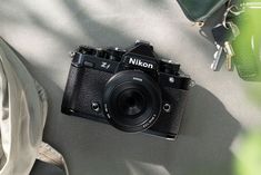 a black camera sitting on top of a table next to a green bag and some keys