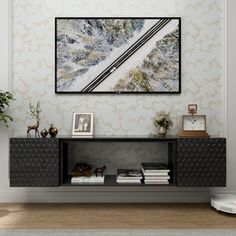 a living room with a painting on the wall next to a book shelf and plant