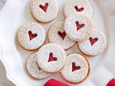 some cookies with hearts on them are sitting on a white plate next to red napkins