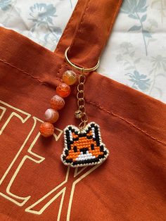 a beaded fox keychain hanging from a tote bag