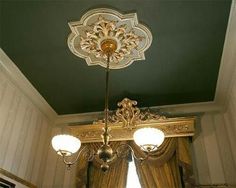 a chandelier hanging from the ceiling in a room with green walls and curtains