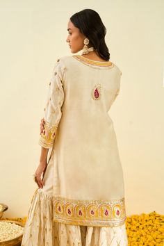 Daisy ivory short kurta with gota patti work and highlighted with basra moti. Paired with embroidered gharara and silk organza glaze mustard dupatta.
Component: 3
Pattern: Embroidered
Type Of Work: Floral, Paisley
Neckline: Round
Sleeve Type: Long Sleeves
Fabric: Kurta and Gharara - Silk Chanderi; Dupatta - Silk Organza
Color: White
Other Details: 
Gota and bead work
Embroidered dupatta
Occasion: Wedding,Mehendi - Aza Fashions Elegant Semi-stitched Sharara With Gota Work, Kundan Straight Kurta Set For Transitional Season, Elegant Sharara With Gota Work For Transitional Season, Unstitched Kundan Palazzo Set With Gota Work, Wedding Sharara With Resham Embroidery And Straight Kurta, Raw Silk Sharara For Eid Wedding, Semi-stitched Chinon Sharara With Gota Work, Chinon Sharara With Gota Work, Raw Silk Sharara With Dabka Work