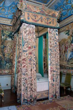 an ornate canopy bed in a bedroom with tapestry work on the walls