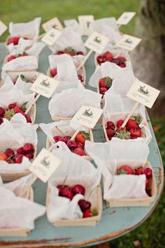 strawberries are in baskets on a table with white napkins and tags attached to them