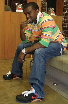 a young man sitting on the steps with his foot up and headphones in his mouth