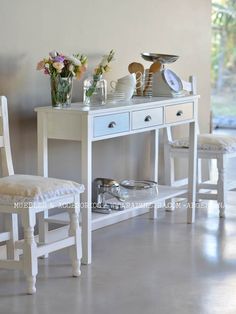 a white table with two chairs next to it and plates on top of the table