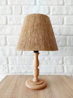 a wooden table with a lamp on it and a white brick wall in the background