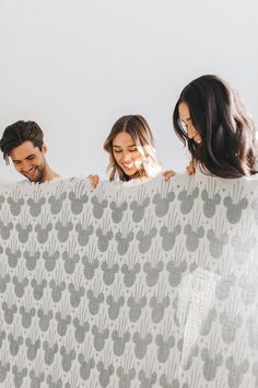 three people standing behind a white and gray blanket