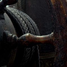 an old wooden wheel with rope on the front and back ends is seen in this close up photo