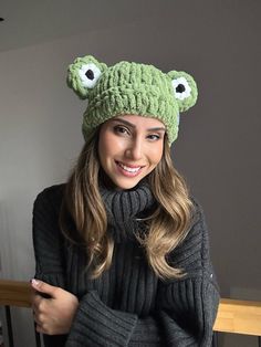 a woman wearing a knitted frog hat and scarf