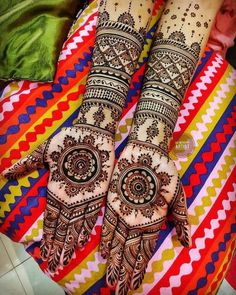 two hands that are decorated with henna and colorful stripes on the bottom, one is holding