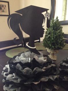 a table topped with black and white paper flowers next to a vase filled with green plants