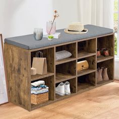 a wooden shelf filled with lots of items on top of a hard wood floor next to a window