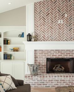 a living room with a fire place and bookshelves on the wall above it