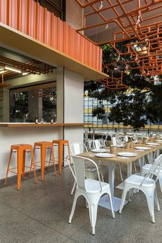 an outdoor dining area with white chairs and orange barstools