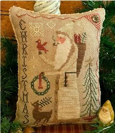 a christmas pillow sitting on top of a wooden table next to a small figurine