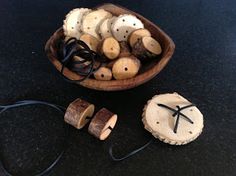 a wooden bowl filled with lots of different types of wood beads and string on top of a table