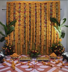 an arrangement of yellow flowers and garlands on a table in front of a wall