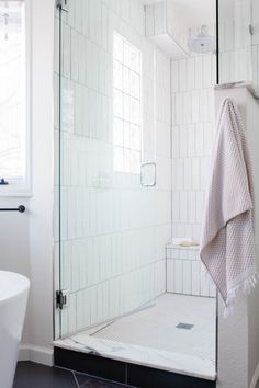 a white tiled bathroom with a glass shower door