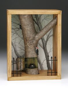 a wooden box with a tree and bird in it