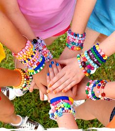 a group of people holding hands together with bracelets on their wrists and one hand in the middle