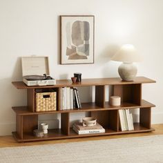 a wooden shelf with books and other items on it in a white living room area