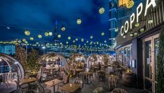 an outdoor dining area with lights strung from the ceiling