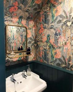 a bathroom with a sink, mirror and colorful wallpaper on the walls in it