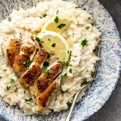 a blue and white plate topped with rice and lemon slices next to a silver fork