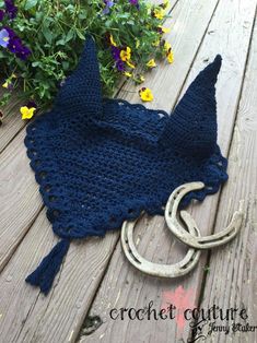 a blue crocheted bag sitting on top of a wooden table next to flowers