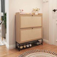 a wooden cabinet with shoes on it in a room next to a door and potted plant