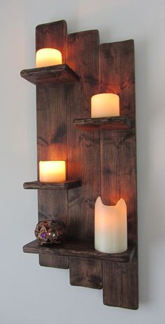 some candles are lit on wooden shelves in front of a wall mounted candle holder that is made out of pallet wood