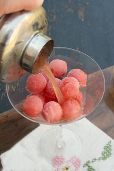 a person pouring something into a glass with watermelon on the rim and in it