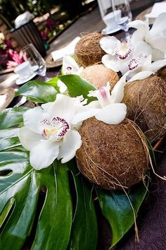 coconuts and flowers are arranged on a table with plates, glasses and utensils