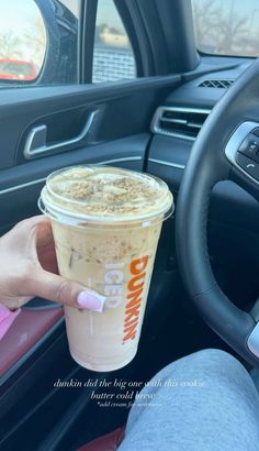 a person holding a drink in their hand while sitting in the driver's seat of a car