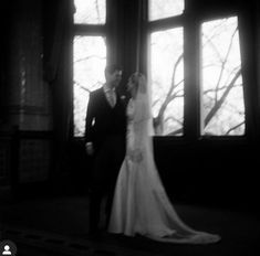 a bride and groom standing in front of two windows