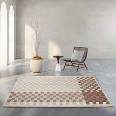 an empty room with a chair, table and potted plant on the floor in front of it