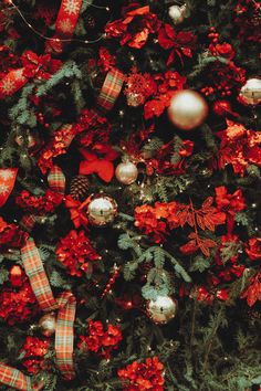 the christmas tree is decorated with red and silver ornaments, bows, and baubles