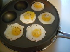 four fried eggs in a frying pan on the stove