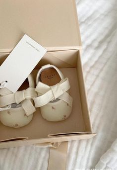 a pair of white baby shoes in a box